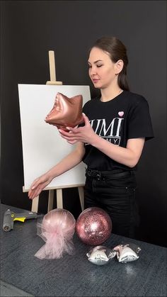 a woman is holding a pair of shoes in front of an easel and some ornaments