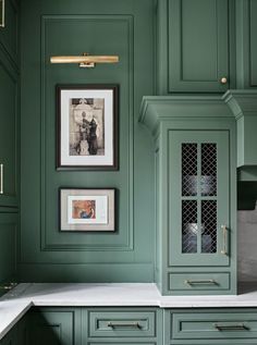 a kitchen with green cabinets and pictures on the wall