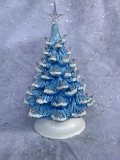 a small blue christmas tree on a white base