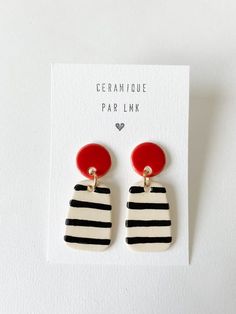 a pair of black and white striped earrings with red accents on the front, sitting on top of a card