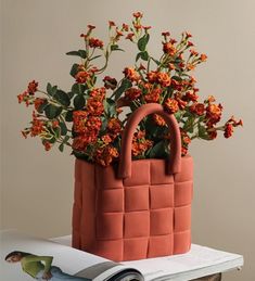 an orange flower pot sitting on top of a table next to a book and magazine