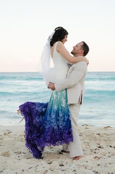 a bride and groom hugging on the beach