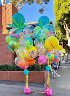 balloons and streamers in the shape of flowers on a sidewalk