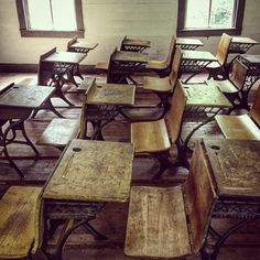 an old school room with wooden desks and chairs in the middle, all empty