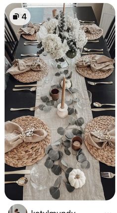 a dining room table set with place settings, napkins and flowers in vases