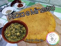 a pizza with spinach and cheese next to a bowl of salsa on a cutting board