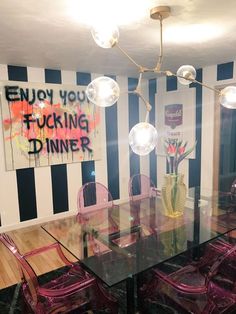 a dining room table with purple chairs and a black and white striped wall behind it