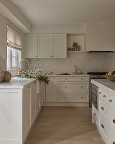 a large kitchen with white cabinets and marble counter tops, along with wooden flooring