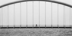 a person riding a bike across a bridge over water