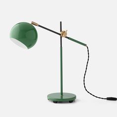 a green table lamp with a black cord attached to it and a white light on top