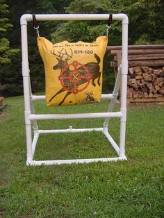 a yellow pillow sitting on top of a white chair in the grass next to a pile of firewood