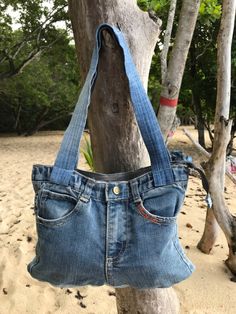 a denim purse hanging from a tree on the beach