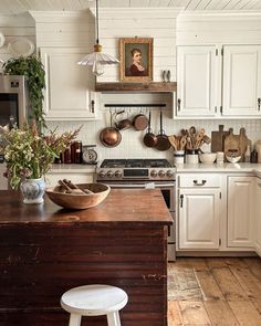 a kitchen with white cabinets and an island in front of the stove top is filled with pots and pans