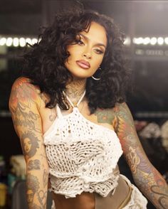 a woman with tattoos on her arm and chest is posing for the camera in a white top