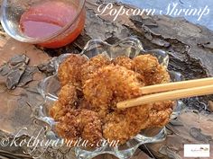 a glass bowl filled with fried food and chopsticks next to a cup of tea