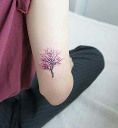 a woman's arm with a small pink tree tattoo on the left inner arm