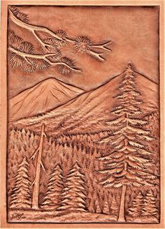 a carved wood panel with trees and mountains in the background