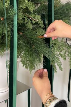 a woman is trimming a christmas tree with scissors