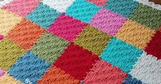 a multicolored crocheted blanket sitting on top of a wooden table