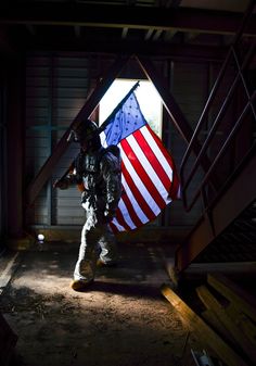 a soldier holding an american flag in the dark