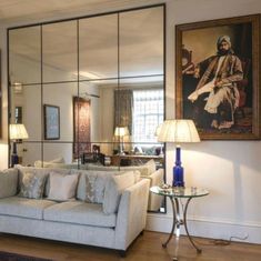 a living room filled with furniture next to a tall mirror wall mounted on the wall