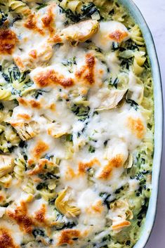 a casserole dish with chicken, spinach and artichokes in it