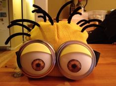 a close up of a toy on a table with two eyes and a spider hat