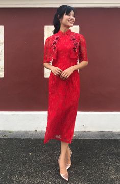 a woman standing in front of a building wearing a red dress