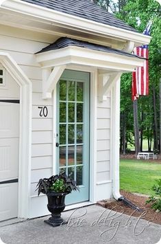 a small white house with an american flag on the front door and window sill