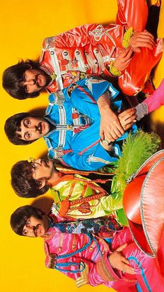 the beatles are posing for a photo in their colorful outfits and holding onto one another's hand