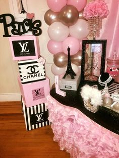 a pink and black paris themed party with balloons, chandeliers, decorations and pictures