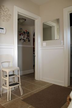 a white chair sitting in the middle of a living room next to a mirror and door