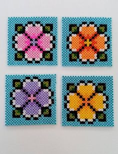 four pieces of beaded art made to look like flower designs on blue and green squares