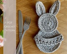 a crocheted bunny hat next to a fork and knife