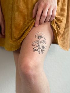 a person with a flower tattoo on their leg, holding onto the thigh of another person's knee