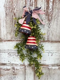 an american flag wreath hanging on the side of a wooden door with greenery around it