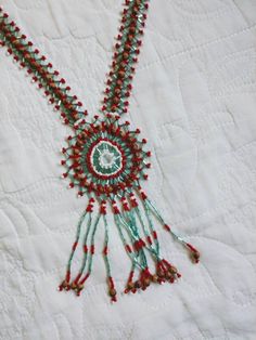 a close up of a beaded necklace on a white quilted piece of cloth