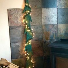 there is a christmas tree with lights on it in front of a wall and fireplace