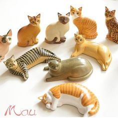 a group of ceramic cats sitting next to each other on top of a white surface