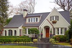 a white house with red door and windows on a rainy day in front of some trees