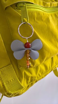 a yellow bag with a red beaded keychain hanging from it's side