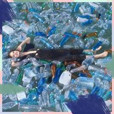 a woman laying on top of a pile of plastic bottles