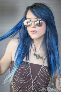 a woman with long blue hair and sunglasses