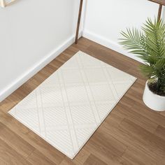 a white rug on the floor next to a potted plant