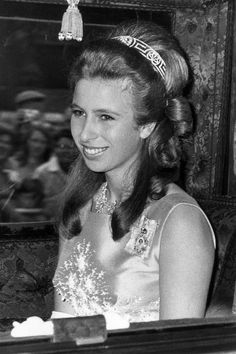 an old black and white photo of a woman in a tiara sitting at a table