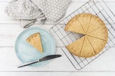 a pie sitting on top of a cooling rack next to a plate with a slice cut out