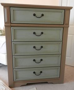 an old dresser is painted green and has black knobs on the drawer pulls, along with a white bed in the background