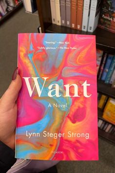 a person holding up a book in front of bookshelves