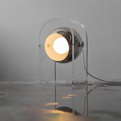 a light that is sitting on top of a glass table next to a white wall