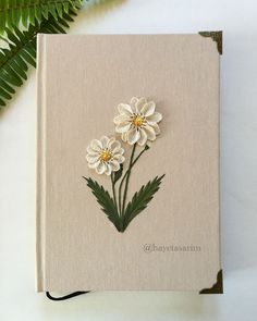 a book with flowers on it sitting next to a plant